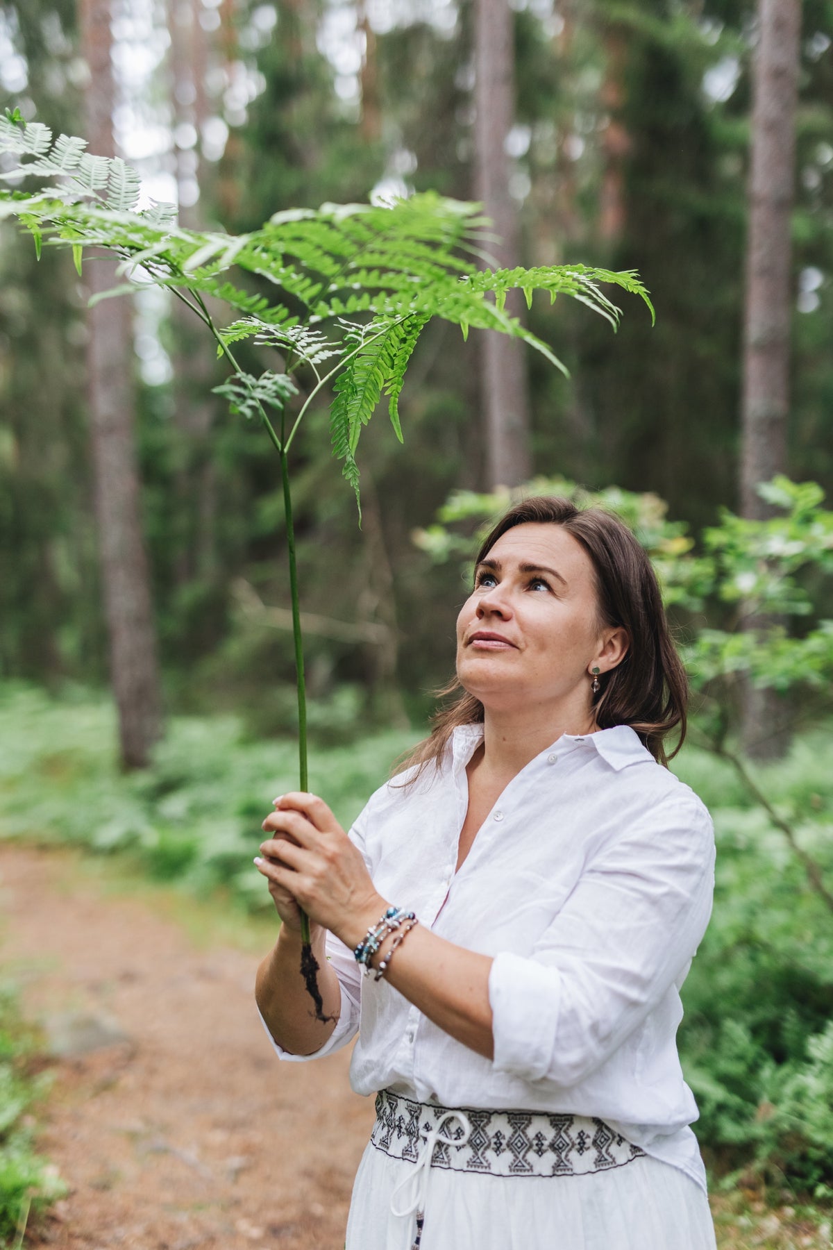 Woman holding a fern in a forest